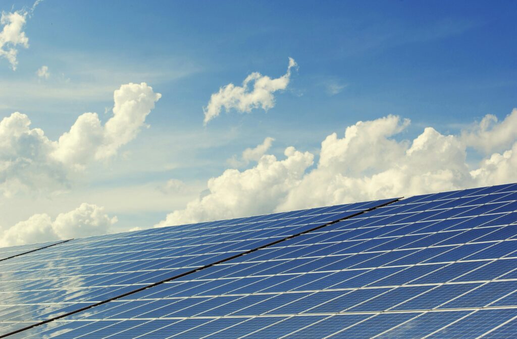 Service-3-min Sleek modern solar panels under a vibrant blue sky with clouds, symbolizing clean energy.